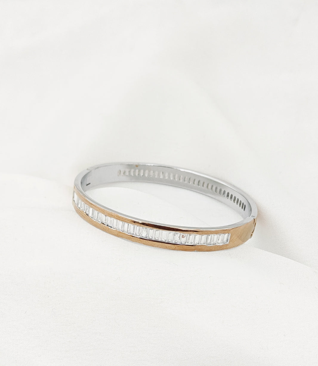 Gold bracelet with clear stones on a white background